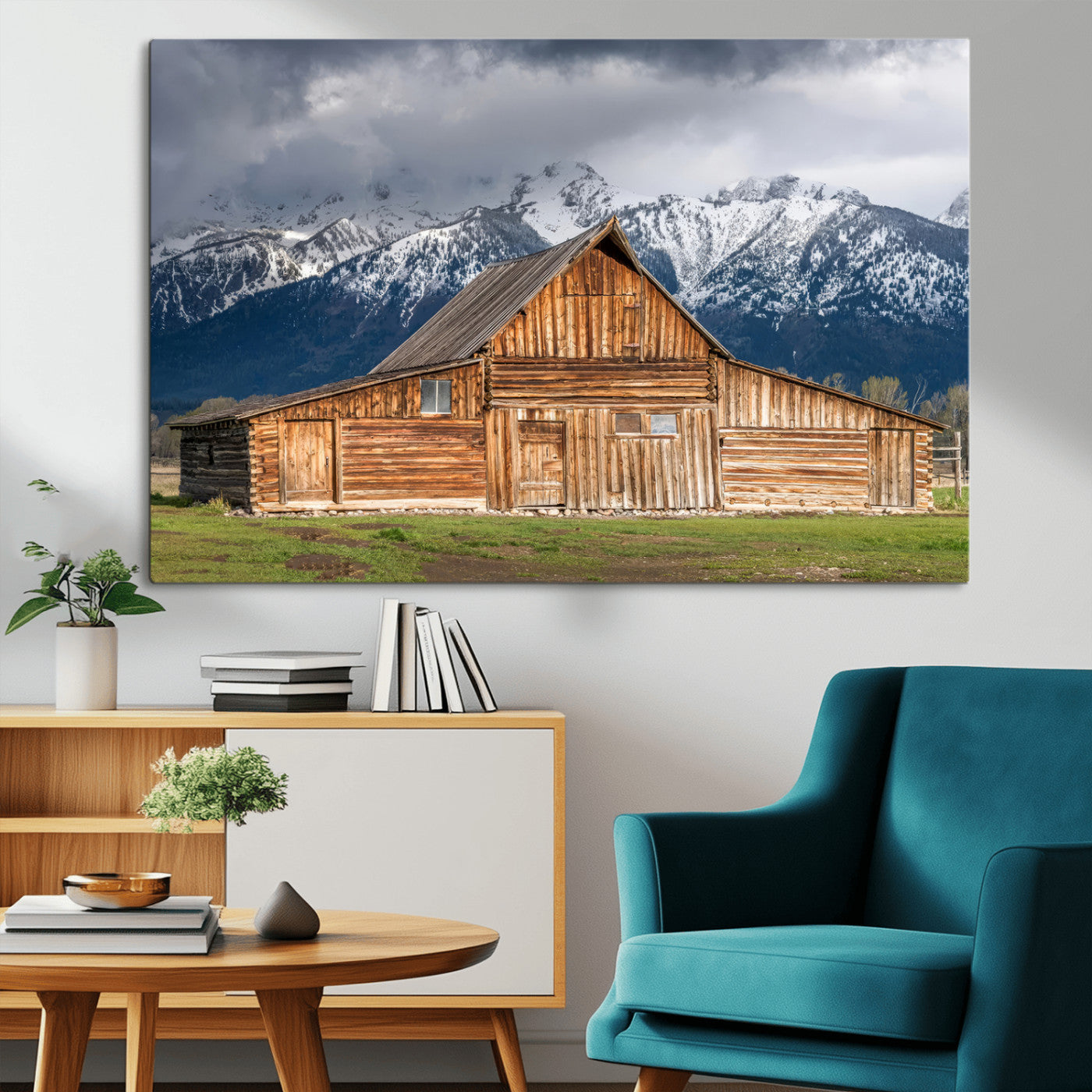 A stunning wall art canvas print featuring a rustic wooden barn set against a backdrop of snow-capped mountains under a dramatic cloudy sky, perfect for adding a touch of rural charm to any space.
