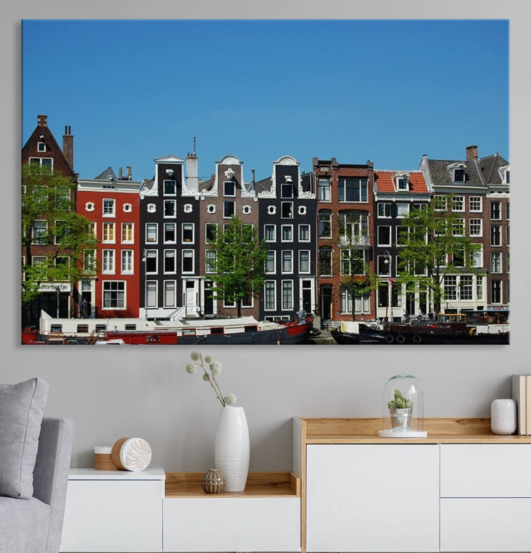 The Amsterdam City Wall Art Canvas Print showcases colorful traditional canal houses and boats set against a clear blue sky.