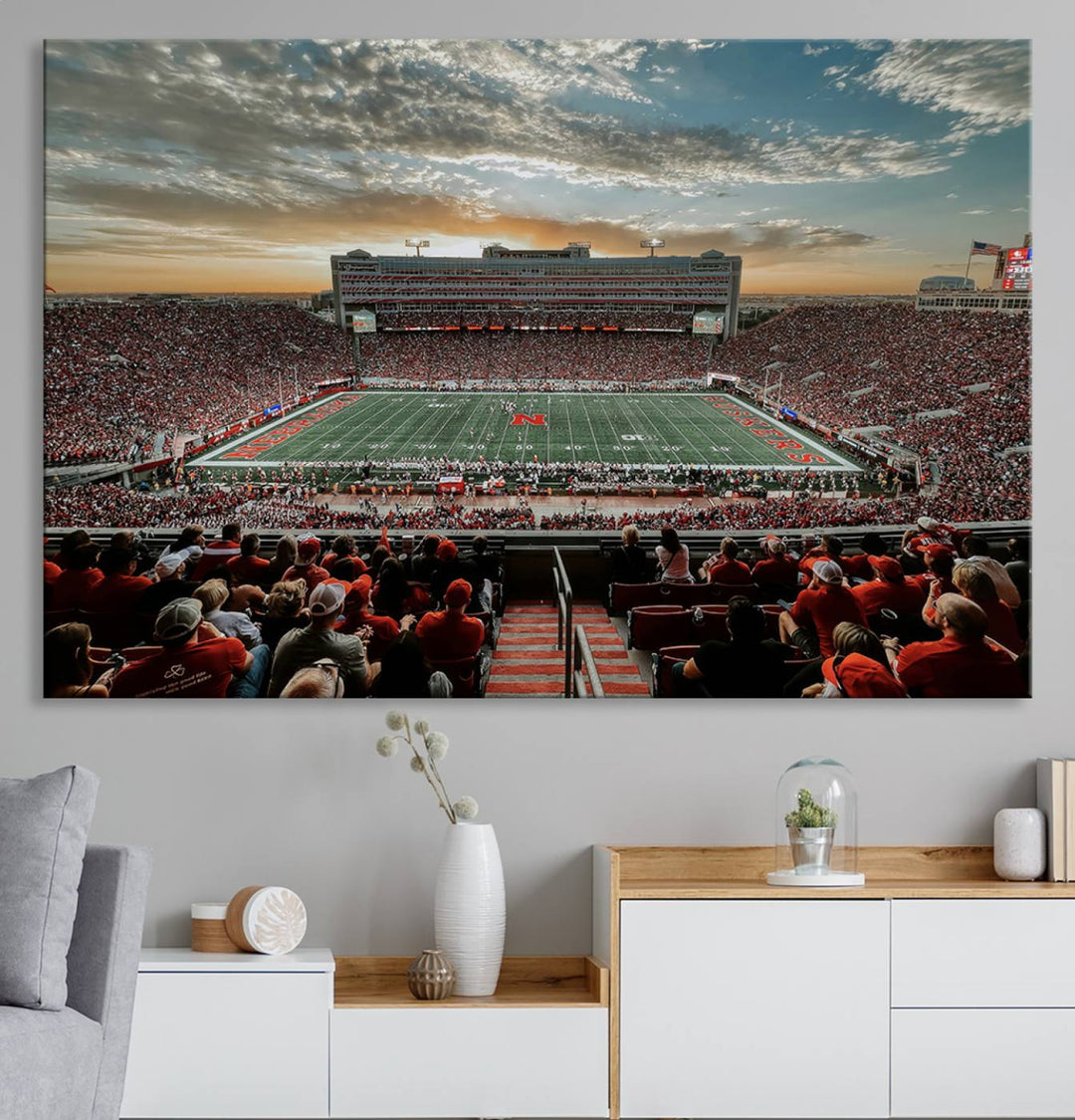 The living room features a stunning triptych of Lincoln Memorial Stadium wall art canvas print, celebrating the University of Nebraska Cornhuskers football team. This piece serves as captivating wall art, showcasing a gallery-quality finish.