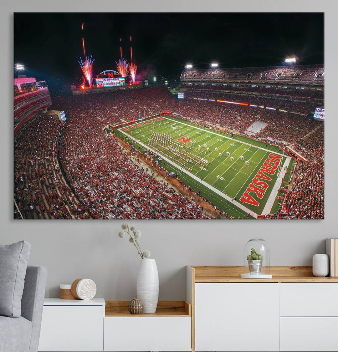 The University of Nebraska Cornhuskers Football Team Print, featuring Lincoln Memorial Stadium in a vibrant triptych canvas with fireworks above and a gallery-quality finish, is elegantly displayed.