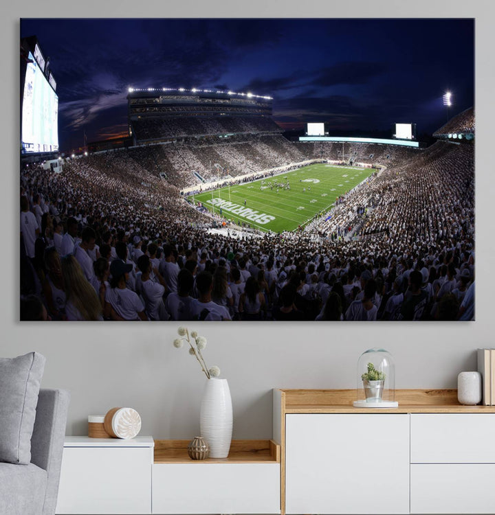 A packed football stadium at night, with bright lights and fans in white, depicted in a Michigan State Spartans Stadium wall art.