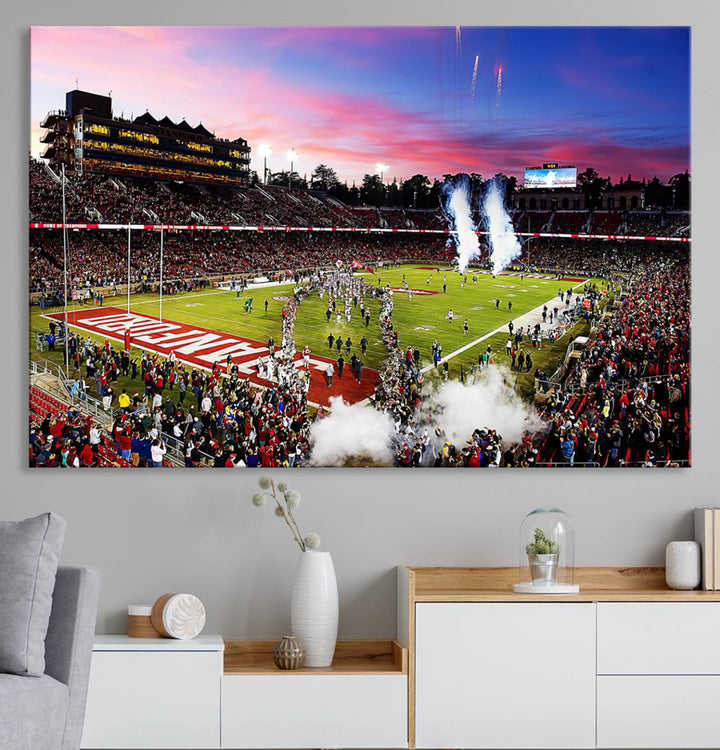 The wall art features a canvas print of the Stanford Cardinal football team, capturing players, fireworks, and smoke against the backdrop of a sunset at Stanford Stadium.