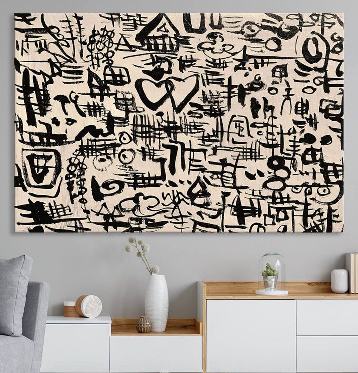 The Abstract Love and Chaos canvas is a museum-quality print featuring black symbols on a beige background, adorned with a heart and scribble design. It is framed to enhance its artistic appeal.