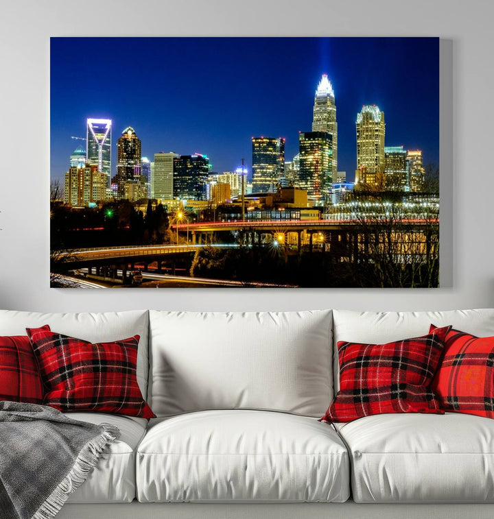 The Charlotte City Lights Night Blue Skyline Cityscape View Wall Art Canvas Print, showcasing an illuminated city skyline at night, is printed on museum-quality canvas with a UV-protective coating. Enhance your space with this stunning piece and enjoy free shipping with your purchase.