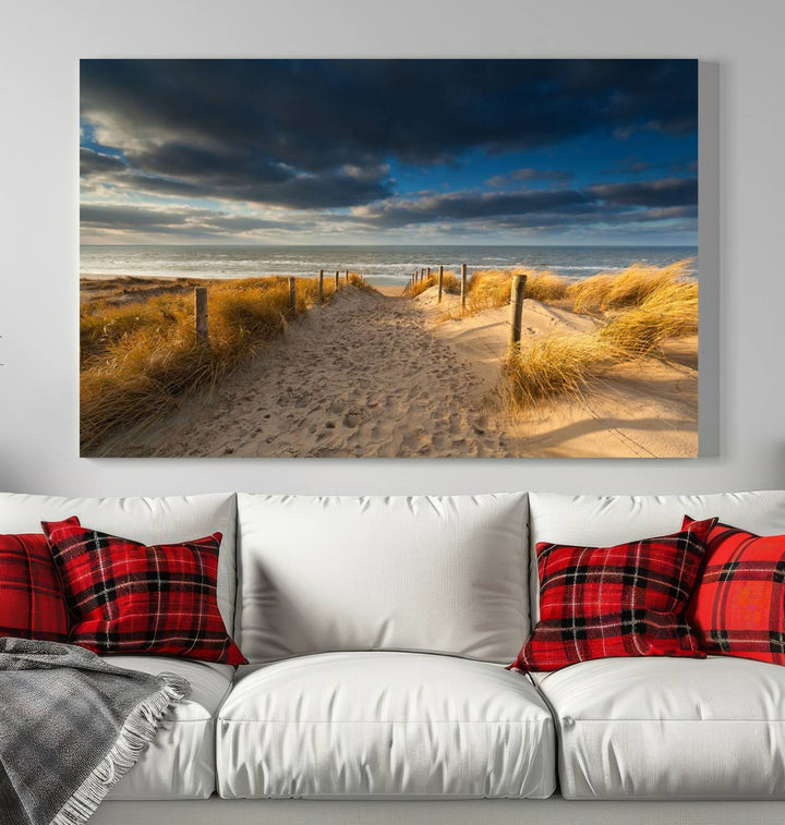 The Ocean Beach Dark Clouds Wall Art Canvas Print is a breathtaking triptych depicting a sandy beach path with tall grasses under an intense cloudy sky. It is crafted on museum-quality canvas with UV protection.