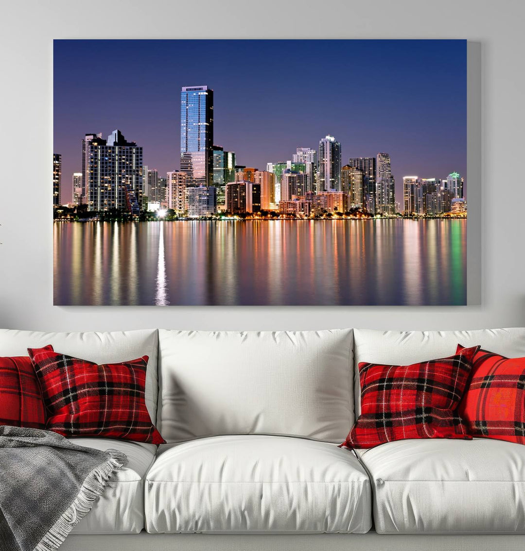 The Miami Skyline Canvas Wall Art Print showcases a vibrant night cityscape and beautifully captures the dazzling colorful lights reflecting on the water. This ready-to-hang triptych adorns the wall, creating a stunning visual centerpiece.