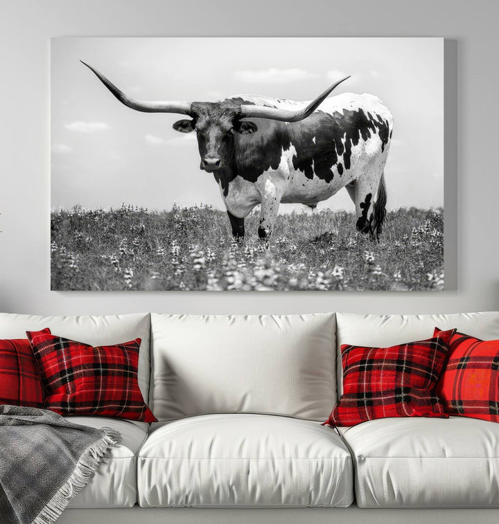 The Texas Black White Highland Longhorn Cow Wall Art Canvas Print, a gallery-quality triptych, elegantly adorns the wall, showcasing a striking black-and-white depiction of a longhorn cow in a field.