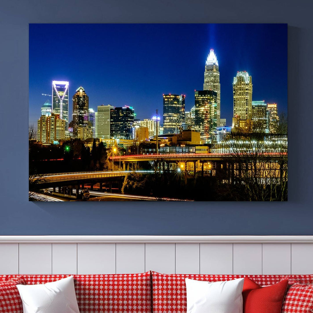 The Charlotte City Lights Night Blue Skyline Cityscape View Wall Art Canvas Print, showcasing an illuminated city skyline at night, is printed on museum-quality canvas with a UV-protective coating. Enhance your space with this stunning piece and enjoy free shipping with your purchase.