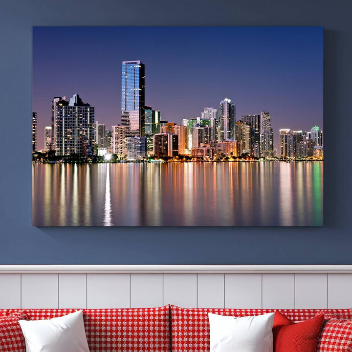 The Miami Skyline Canvas Wall Art Print showcases a vibrant night cityscape and beautifully captures the dazzling colorful lights reflecting on the water. This ready-to-hang triptych adorns the wall, creating a stunning visual centerpiece.