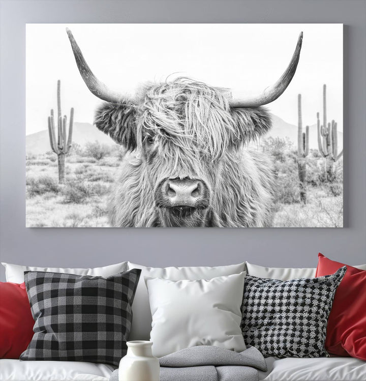 The "Rustic Charm | Cow Longhorn Black White Bighorn Wall Art Canvas Print" is a stunning triptych that showcases a highland cow with long horns set against a desert landscape with cacti in the background. This farmhouse wall art elevates any room into a rustic haven with its gallery-quality canvas.