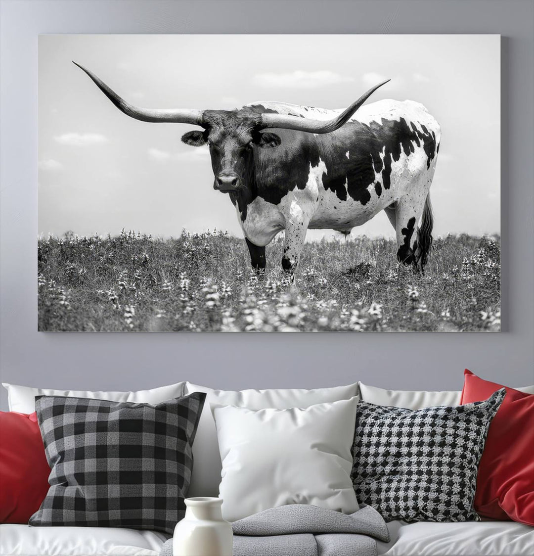 The Texas Black White Highland Longhorn Cow Wall Art Canvas Print, a gallery-quality triptych, elegantly adorns the wall, showcasing a striking black-and-white depiction of a longhorn cow in a field.