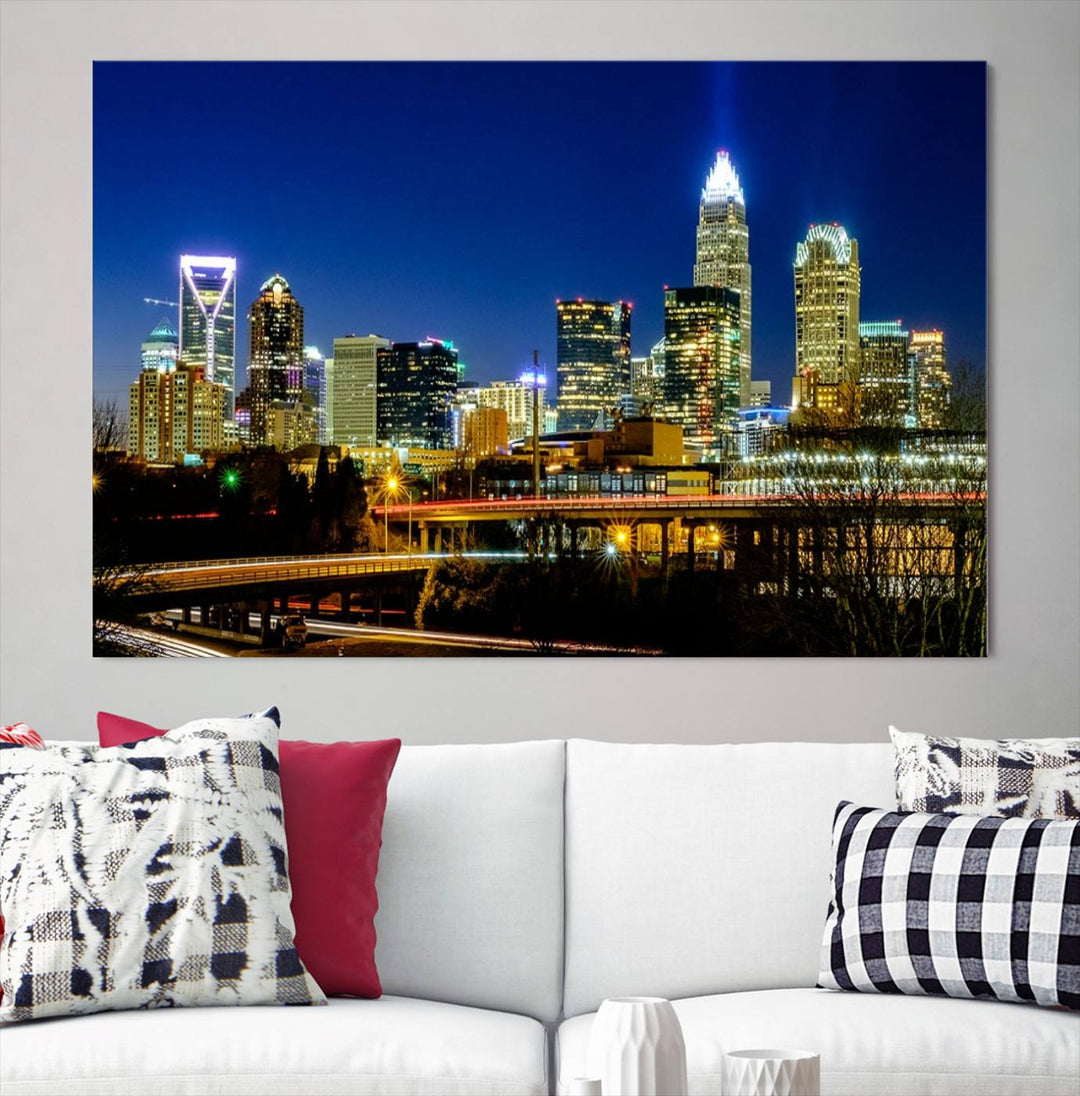 The Charlotte City Lights Night Blue Skyline Cityscape View Wall Art Canvas Print, showcasing an illuminated city skyline at night, is printed on museum-quality canvas with a UV-protective coating. Enhance your space with this stunning piece and enjoy free shipping with your purchase.