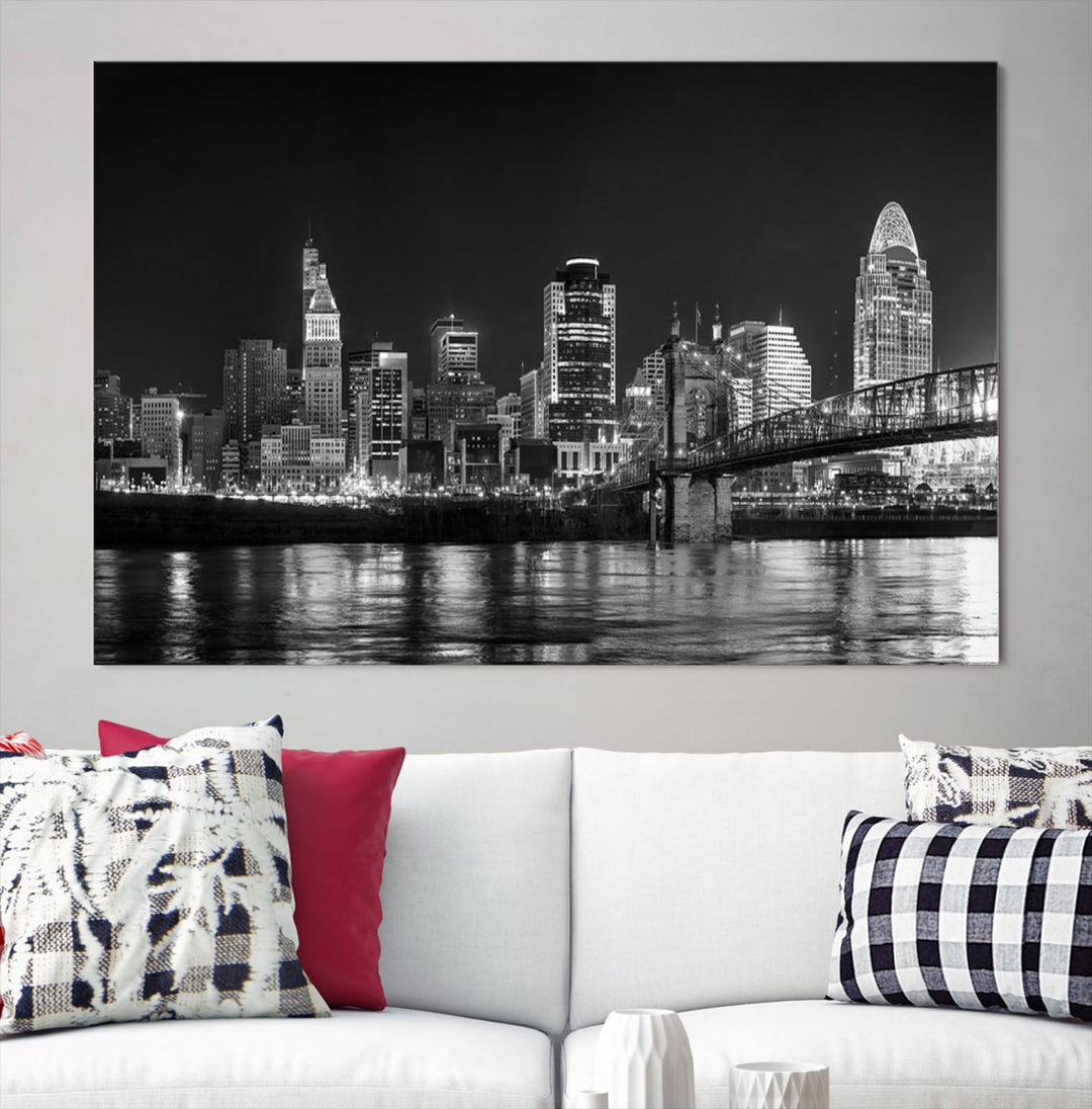 The Cincinnati City Lights Skyline Black and White Wall Art Cityscape Canvas Print elegantly adorns a modern living room. This museum-quality canvas triptych of a city skyline is enhanced by hand-assembled frames for added finesse, and you can enjoy free shipping on this stunning home addition.