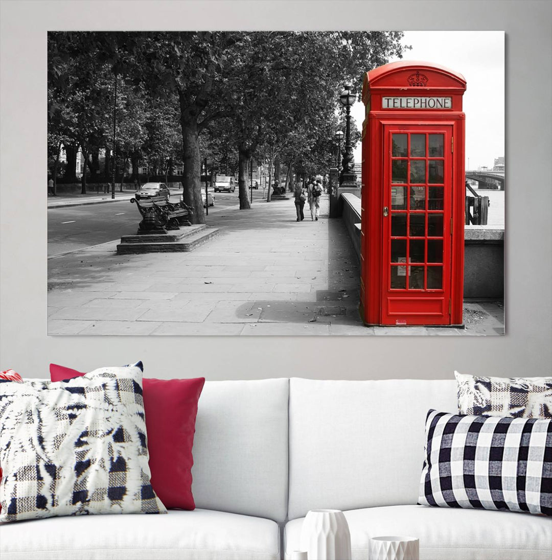 The London Phone Club Wall Art is a stunning piece that showcases a red telephone box set in a black and white street scene on museum-quality canvas. It is gallery wrapped with a UV-protective coating to preserve its vibrant charm.