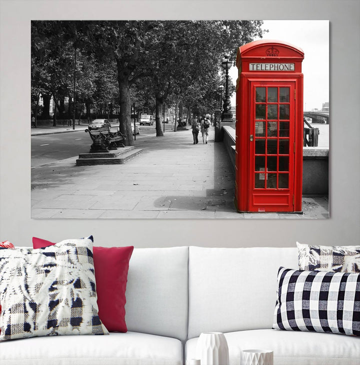 The London Phone Club Wall Art is a stunning piece that showcases a red telephone box set in a black and white street scene on museum-quality canvas. It is gallery wrapped with a UV-protective coating to preserve its vibrant charm.