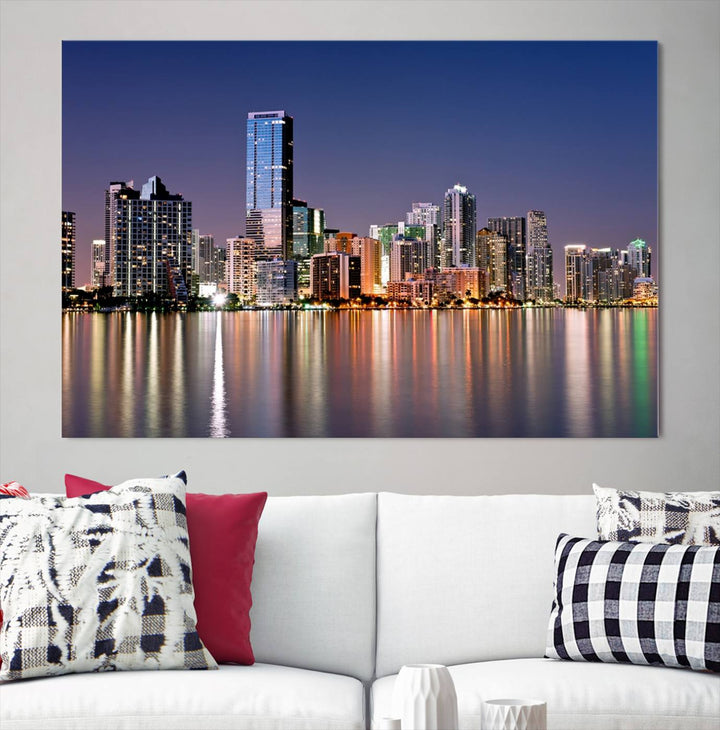 The Miami Skyline Canvas Wall Art Print showcases a vibrant night cityscape and beautifully captures the dazzling colorful lights reflecting on the water. This ready-to-hang triptych adorns the wall, creating a stunning visual centerpiece.