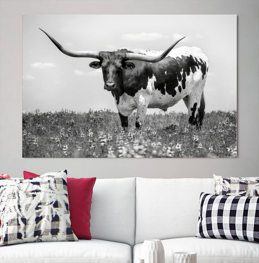 The Texas Black White Highland Longhorn Cow Wall Art Canvas Print, a gallery-quality triptych, elegantly adorns the wall, showcasing a striking black-and-white depiction of a longhorn cow in a field.