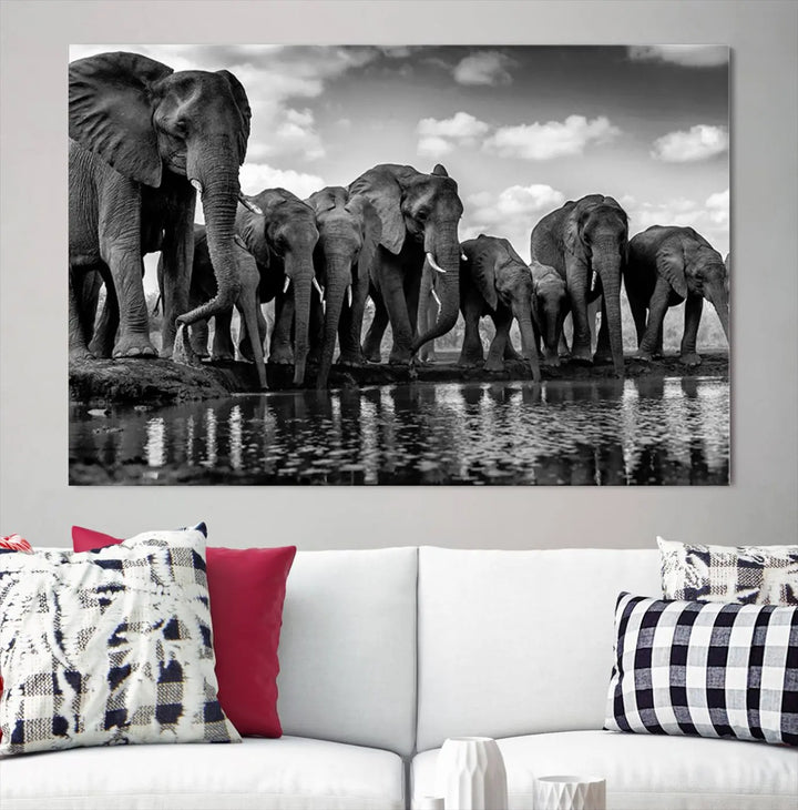 A stunning "Wall Art Animal Canvas Print" featuring a black and white photo of a herd of elephants drinking water is elegantly displayed, gallery wrapped on museum-quality canvas.