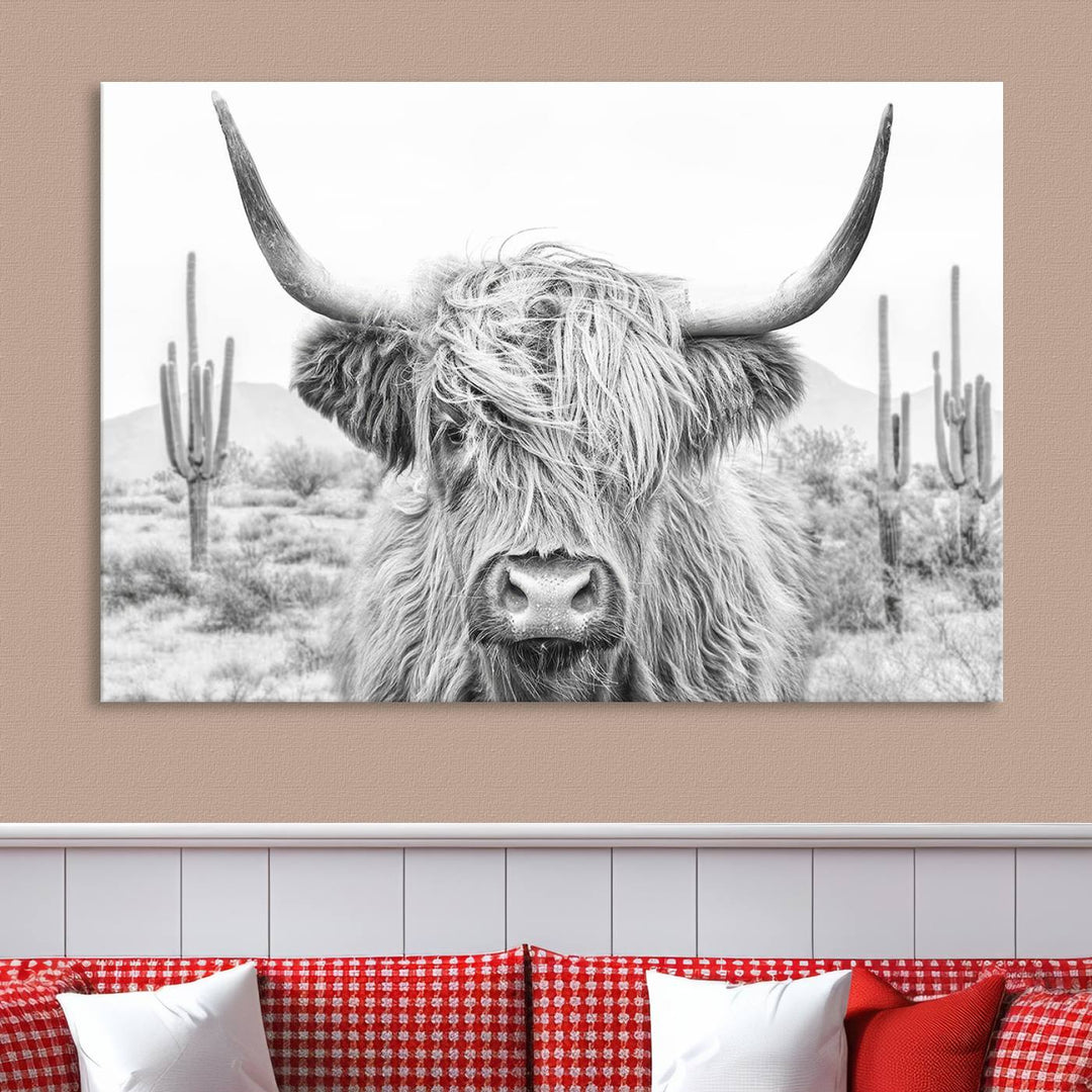 The "Rustic Charm | Cow Longhorn Black White Bighorn Wall Art Canvas Print" is a stunning triptych that showcases a highland cow with long horns set against a desert landscape with cacti in the background. This farmhouse wall art elevates any room into a rustic haven with its gallery-quality canvas.