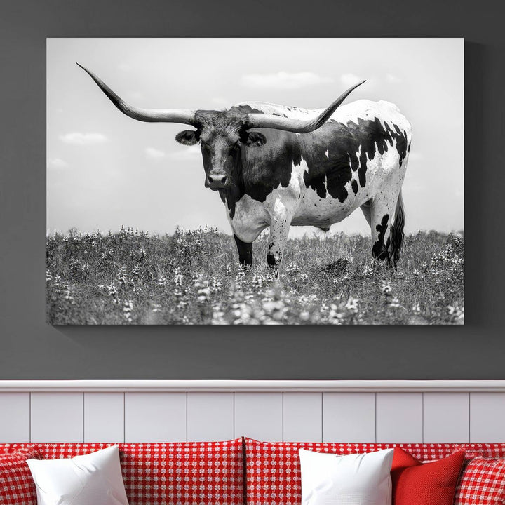 The Texas Black White Highland Longhorn Cow Wall Art Canvas Print, a gallery-quality triptych, elegantly adorns the wall, showcasing a striking black-and-white depiction of a longhorn cow in a field.