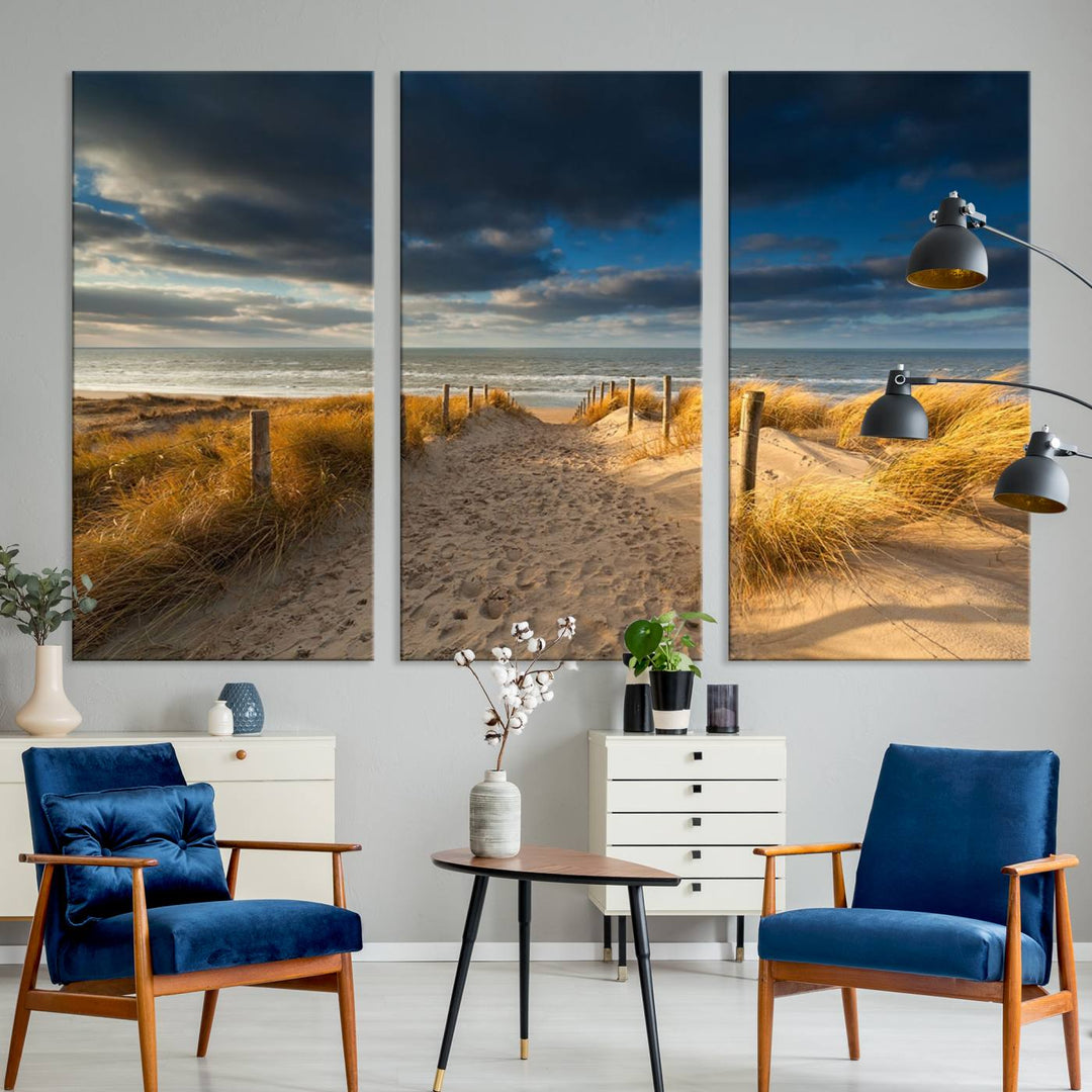 The Ocean Beach Dark Clouds Wall Art Canvas Print is a breathtaking triptych depicting a sandy beach path with tall grasses under an intense cloudy sky. It is crafted on museum-quality canvas with UV protection.