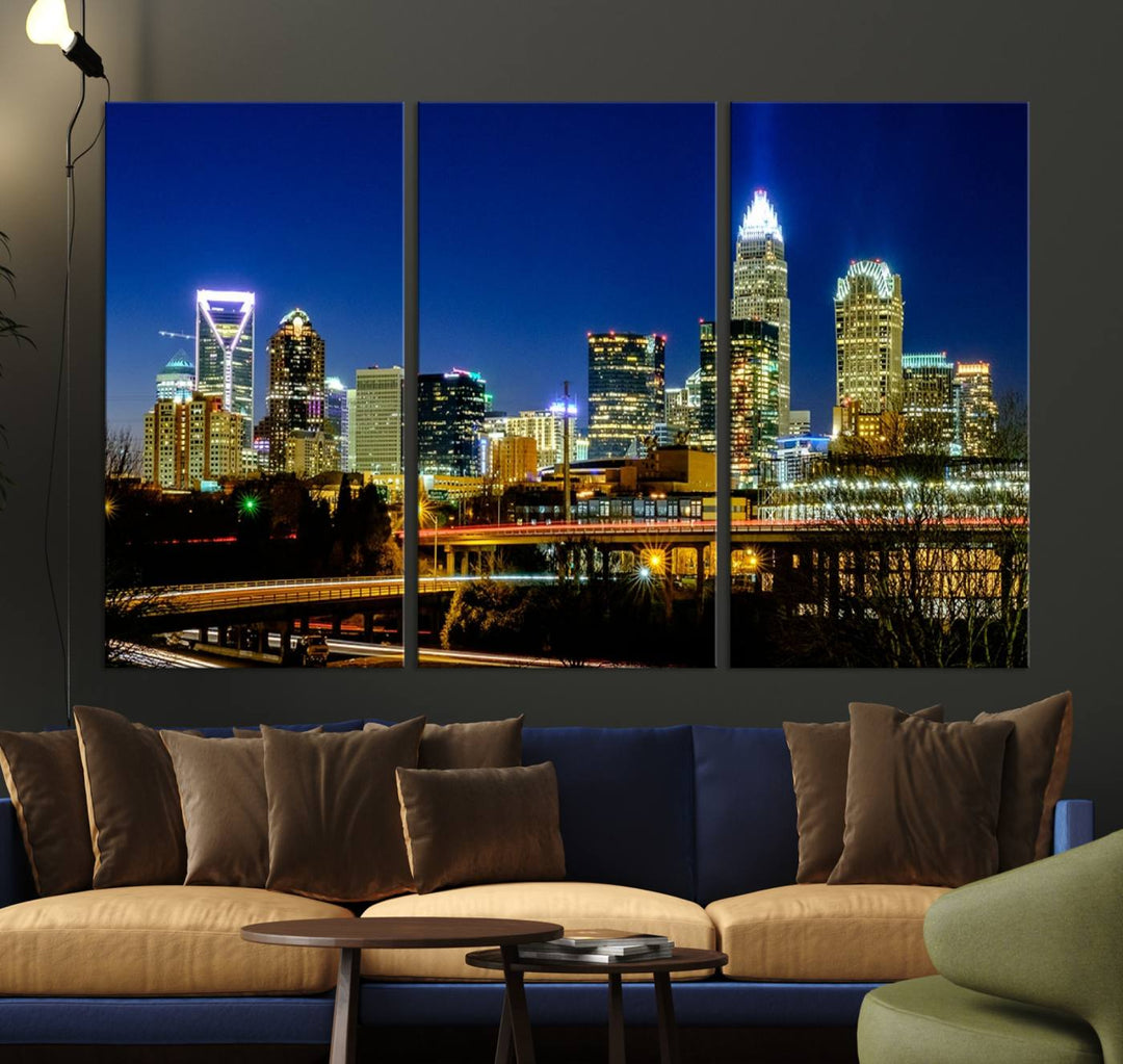 The Charlotte City Lights Night Blue Skyline Cityscape View Wall Art Canvas Print, showcasing an illuminated city skyline at night, is printed on museum-quality canvas with a UV-protective coating. Enhance your space with this stunning piece and enjoy free shipping with your purchase.