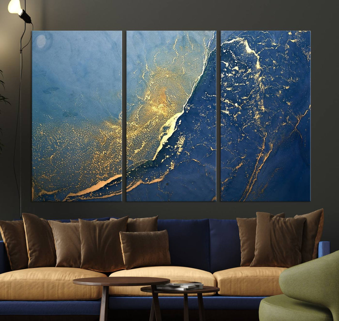 The Navy Blue Yellow Twinkle Wall Art Canvas Print, featuring an abstract design in gold and blue, enhances a modern living room as it adorns a white wall with its gallery-wrapped, museum-quality canvases for an exquisite touch.