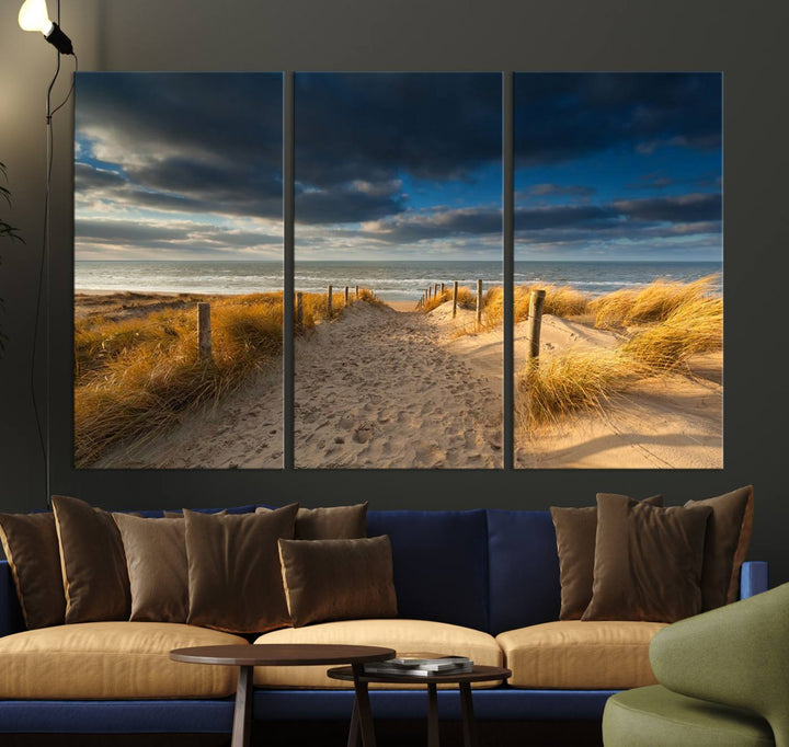 The Ocean Beach Dark Clouds Wall Art Canvas Print is a breathtaking triptych depicting a sandy beach path with tall grasses under an intense cloudy sky. It is crafted on museum-quality canvas with UV protection.