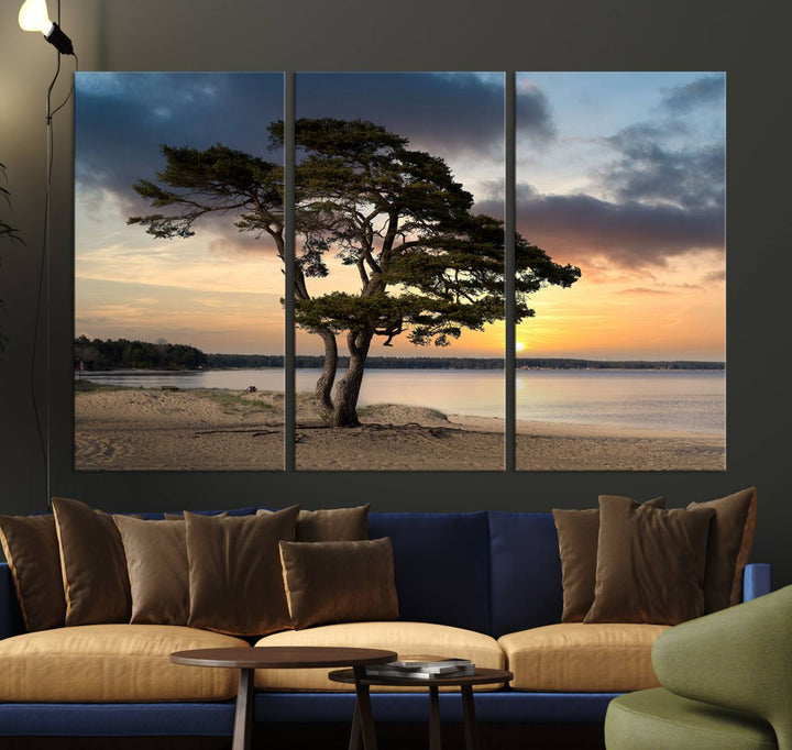 The room showcases the Coastal Sunset Wall Art Canvas Print, a triptych elegantly displayed on museum-quality polycotton canvas, depicting a serene beach sunset with a tree.