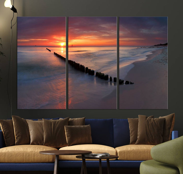 In a modern living room, the Sunset Beach Wall Art Canvas Print is displayed above. This triptych, printed on museum-quality canvas with a UV-protective coating, ensures lasting brilliance. It's ready to hang and brings an elegant touch to your space.