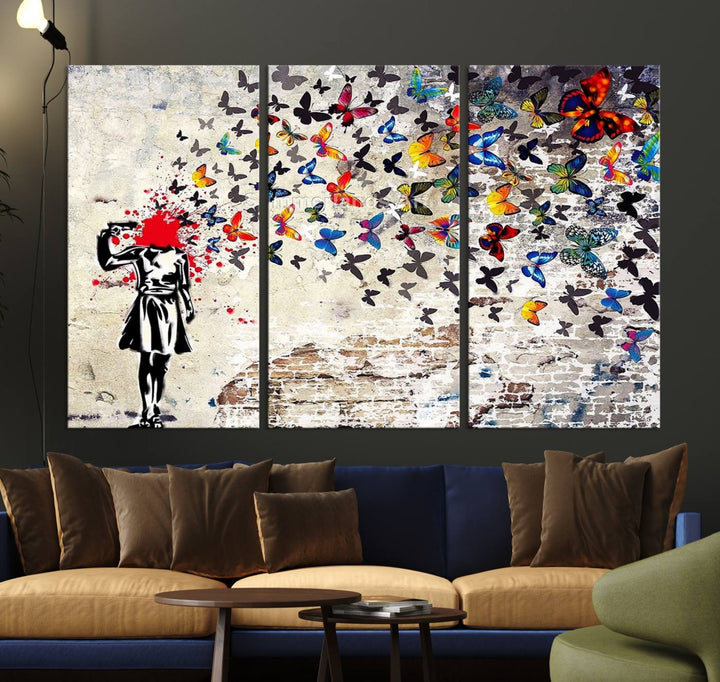 The Banksy Art Butterfly Girl Explosion Canvas showcases a dynamic figure with butterflies bursting from their head, set against a textured wall background. This vibrant urban graffiti piece is perfect for modern interiors and comes ready to hang.