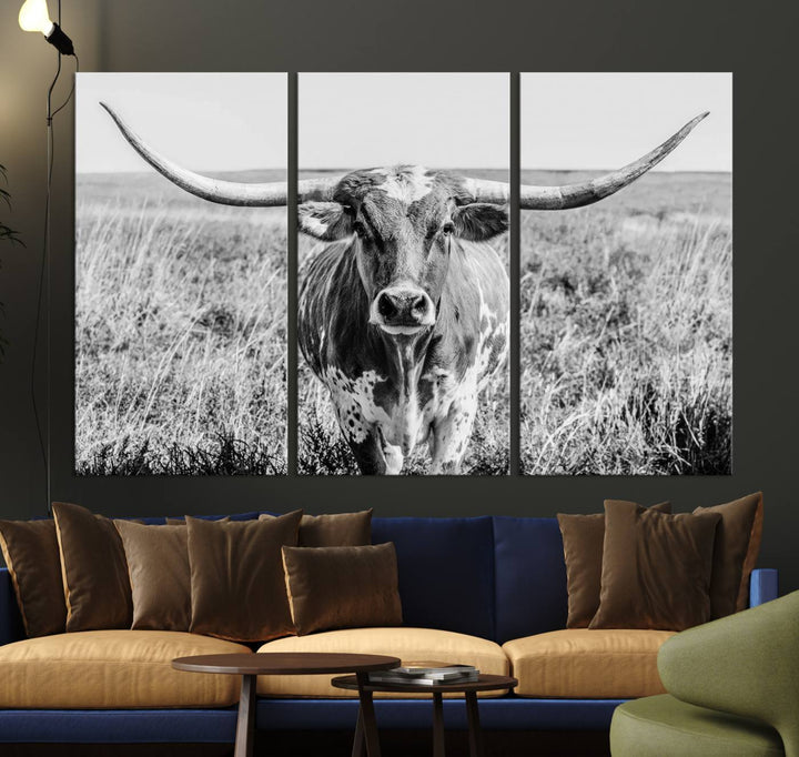 The Texas Cow Longhorn Wall Art Canvas Print is a black and white triptych depicting a cow in a field. It is crafted with museum-quality canvas and features a UV-protective coating.