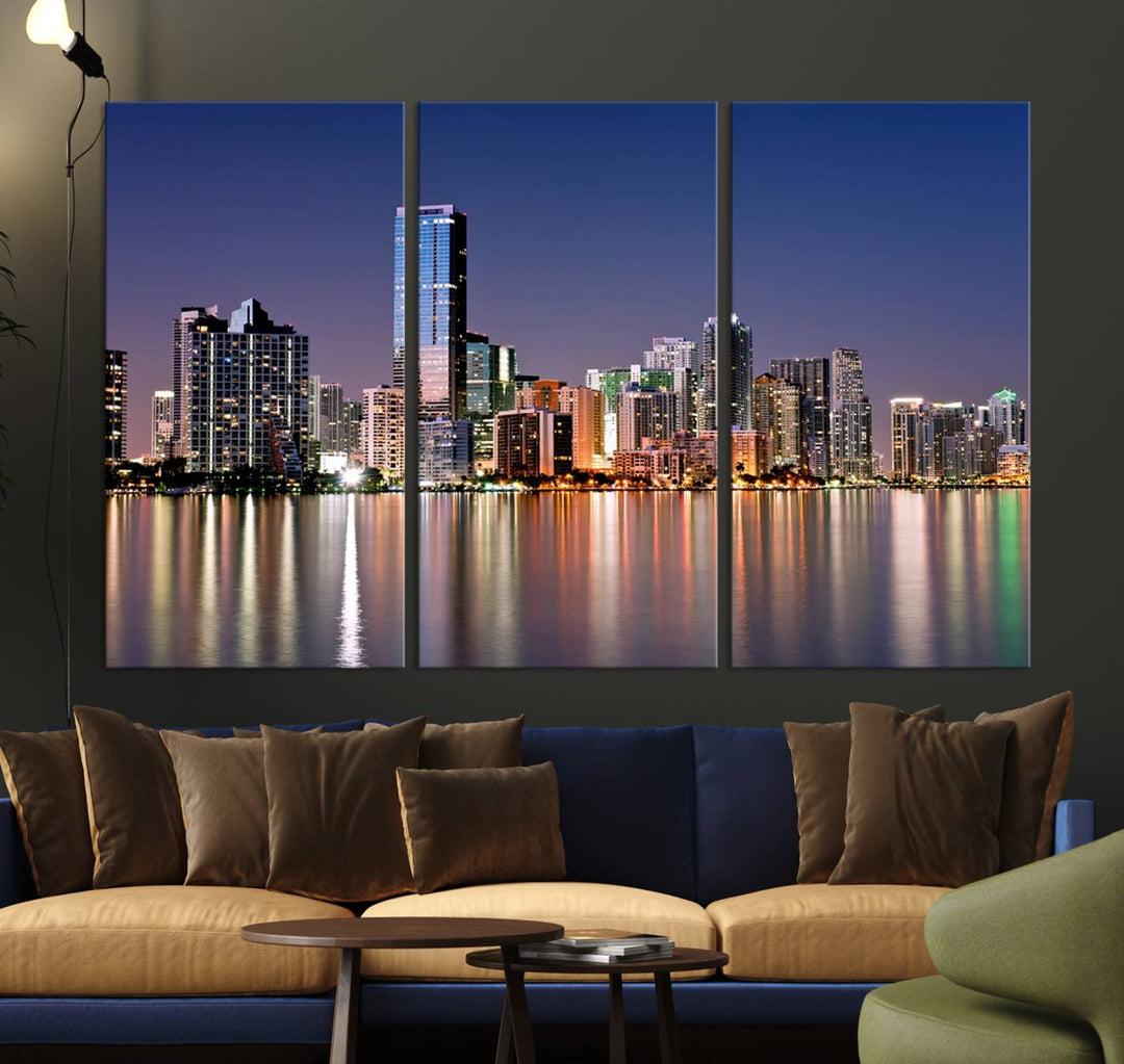 The Miami Skyline Canvas Wall Art Print showcases a vibrant night cityscape and beautifully captures the dazzling colorful lights reflecting on the water. This ready-to-hang triptych adorns the wall, creating a stunning visual centerpiece.