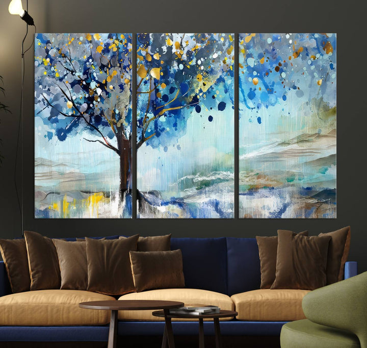 A modern living room features a three-panel Watercolor Style Abstract Tree Printing Wall Art Canvas in vibrant blue and yellow, crafted on museum-quality material.