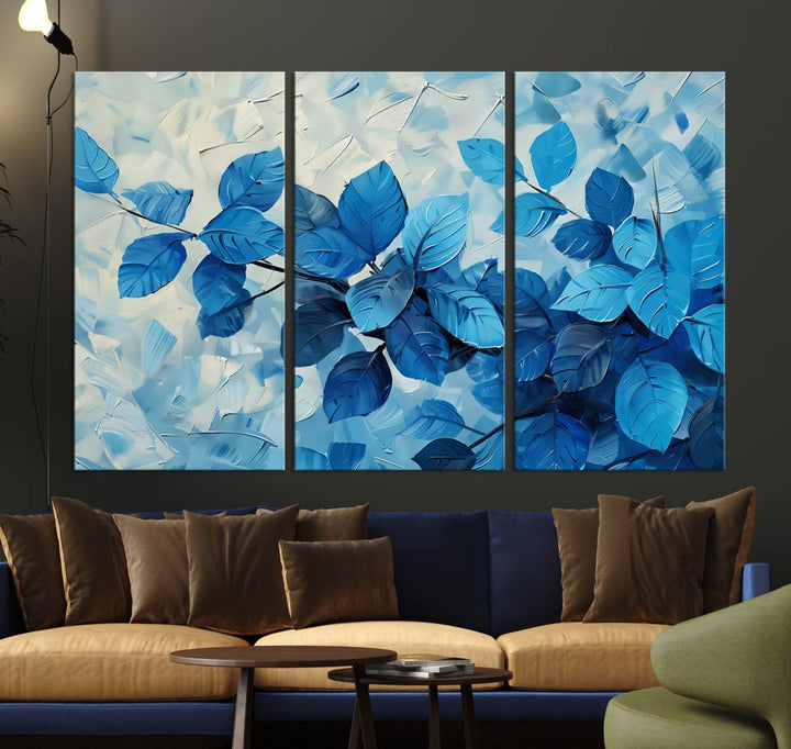 The contemporary living room is highlighted by the Abstract Blue Leaf Wall Art Canvas Print on the wall. The hand-assembled framed art enhances the room's vibrant decor, crafting a gallery-worthy ambience.