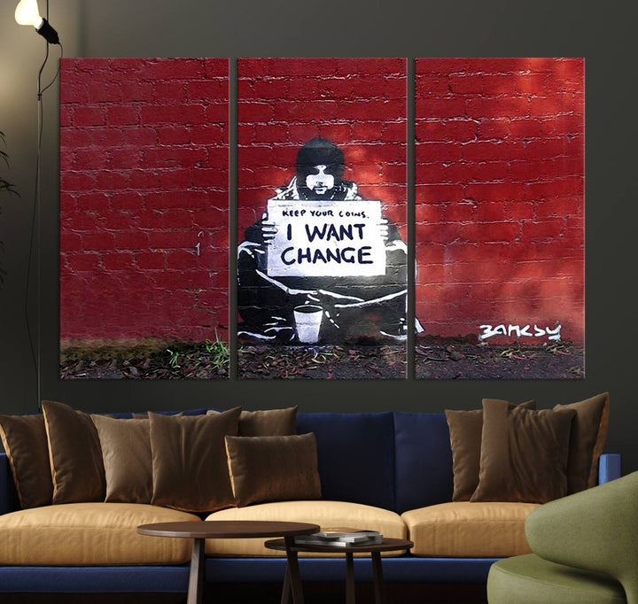 The living room showcases a triptych of stencil artwork on museum-quality canvas, featuring the Banksy I Want Change Graffiti Abstract Wall Art Canvas Print. This captivating piece depicts a person holding a sign that says "I want change" and is finished with a UV-protective coating to ensure long-lasting beauty.