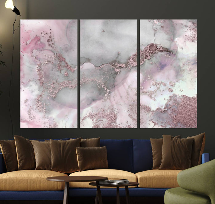 The Rose Marble Abstract Wall Art Canvas Print is a stunning triptych that showcases pink and gray tones, elegantly presented on a dark wall.