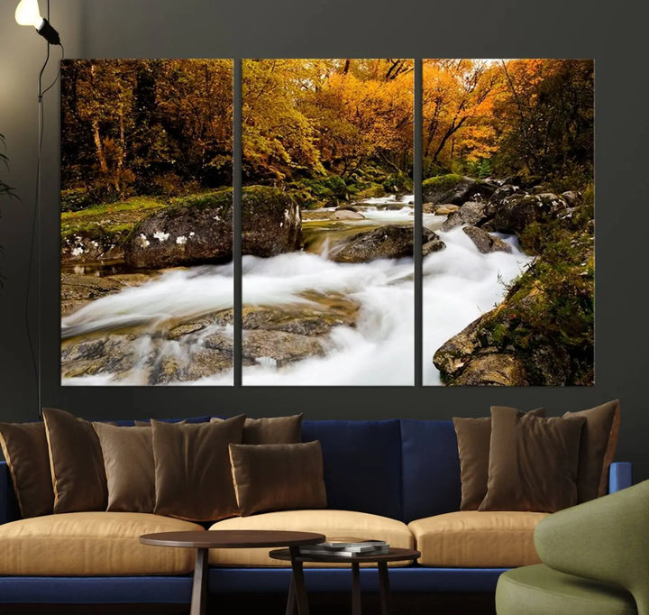 The living room is adorned with the "Wall Art Waterfall Canvas Print River in Forest in Autumn," a triptych on museum-quality canvas showcasing a flowing river surrounded by autumn trees. This ready-to-hang artwork features a UV-protective coating to ensure enduring vibrancy.