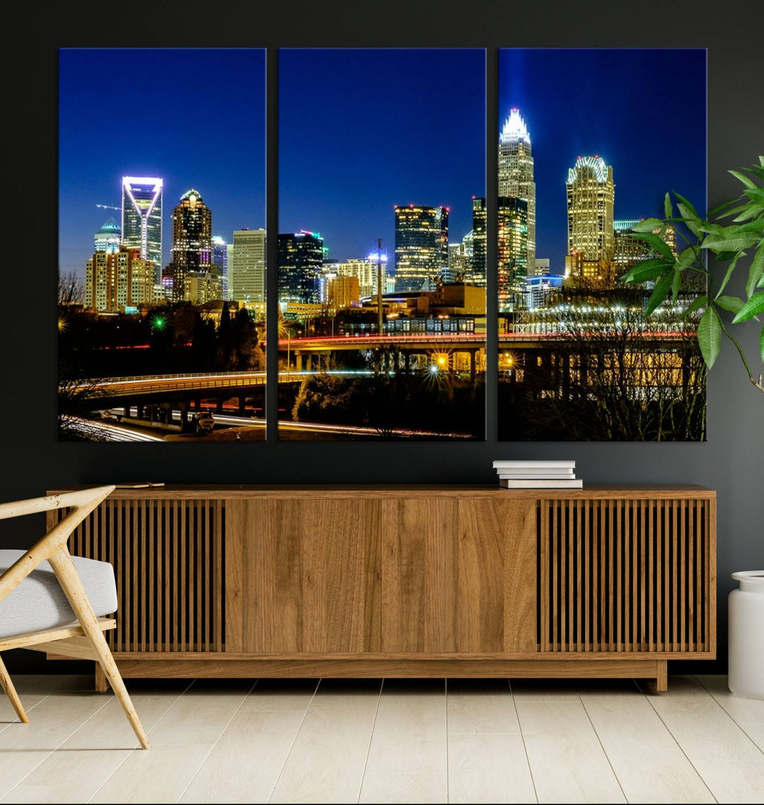 The Charlotte City Lights Night Blue Skyline Cityscape View Wall Art Canvas Print, showcasing an illuminated city skyline at night, is printed on museum-quality canvas with a UV-protective coating. Enhance your space with this stunning piece and enjoy free shipping with your purchase.