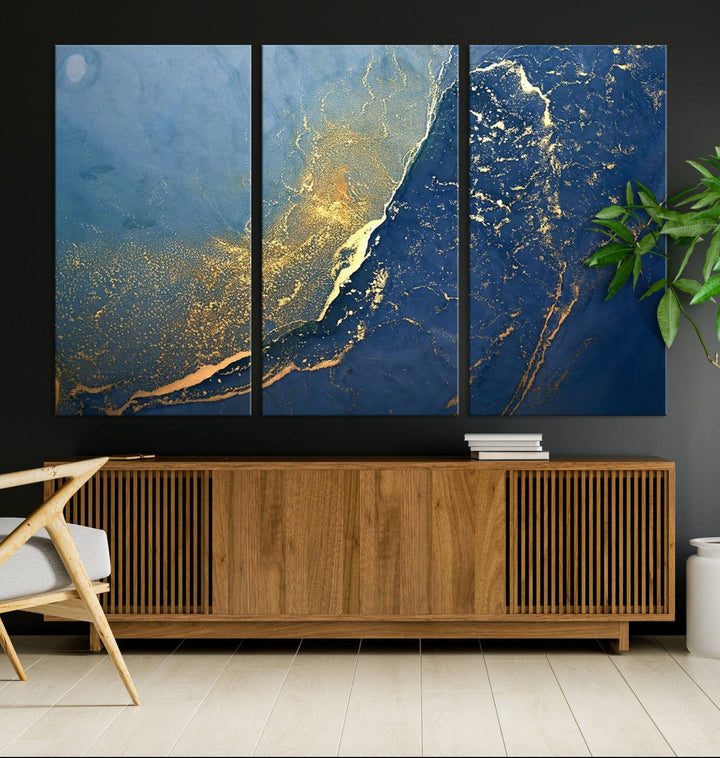 The Navy Blue Yellow Twinkle Wall Art Canvas Print, featuring an abstract design in gold and blue, enhances a modern living room as it adorns a white wall with its gallery-wrapped, museum-quality canvases for an exquisite touch.