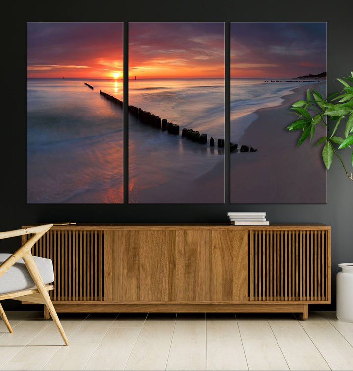 In a modern living room, the Sunset Beach Wall Art Canvas Print is displayed above. This triptych, printed on museum-quality canvas with a UV-protective coating, ensures lasting brilliance. It's ready to hang and brings an elegant touch to your space.