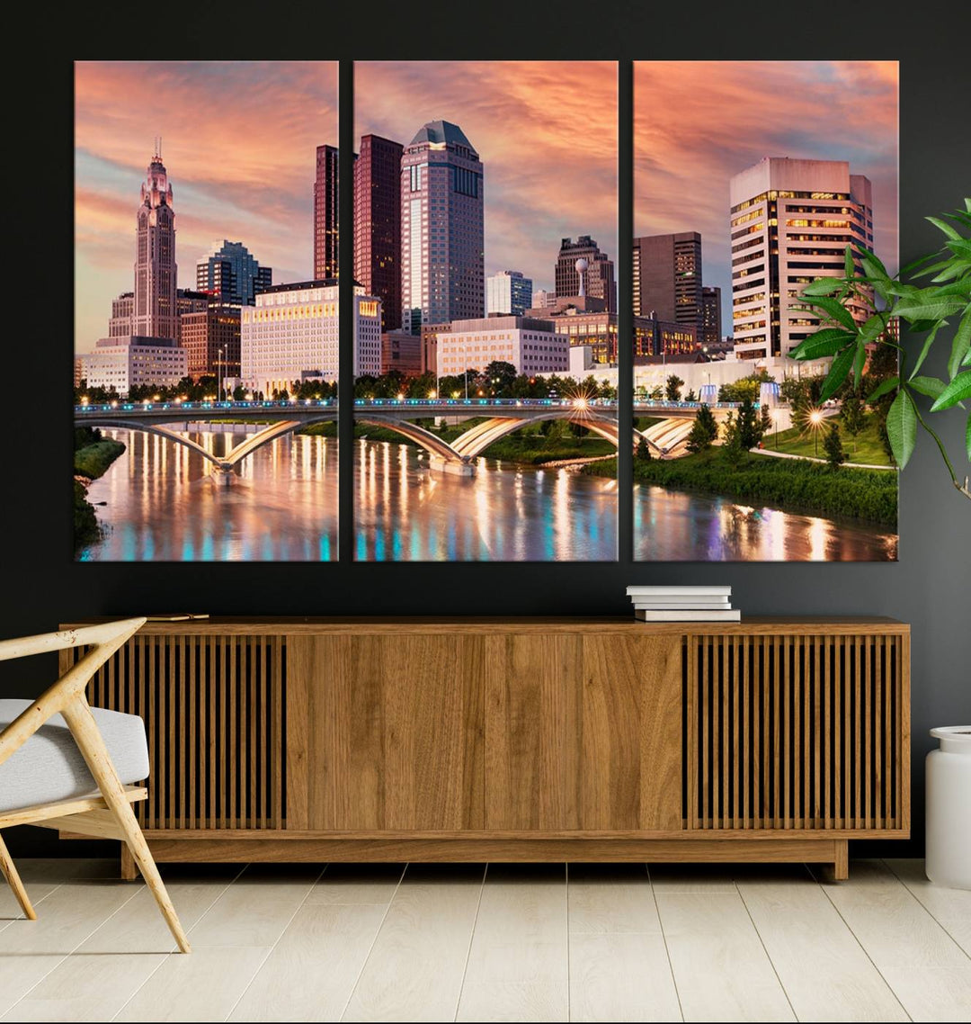 The "Columbus City Lights Sunset Orange Cloudy Skyline Cityscape View" wall art is featured on the wall. This triptych is printed on museum-quality canvas and includes a UV-protective coating, ensuring lasting vibrancy.