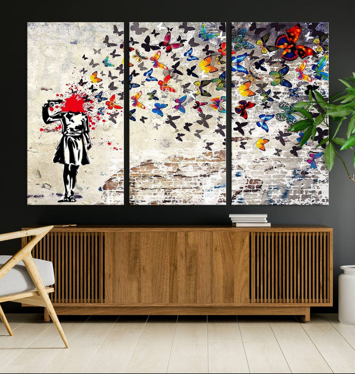 The Banksy Art Butterfly Girl Explosion Canvas showcases a dynamic figure with butterflies bursting from their head, set against a textured wall background. This vibrant urban graffiti piece is perfect for modern interiors and comes ready to hang.