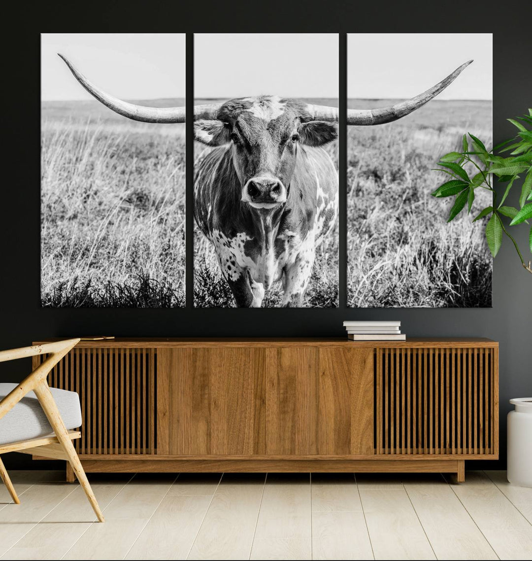 The Texas Cow Longhorn Wall Art Canvas Print is a black and white triptych depicting a cow in a field. It is crafted with museum-quality canvas and features a UV-protective coating.