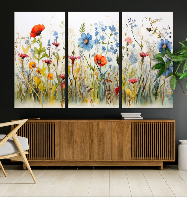 The Colorful Wildflower Canvas Wall Art – Vibrant Floral Botanical Print, consisting of a large 3 panel set, adds bright nature decor to the living room against a black wall.