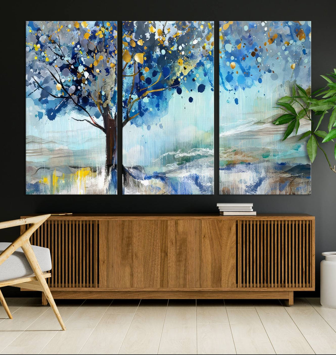 A modern living room features a three-panel Watercolor Style Abstract Tree Printing Wall Art Canvas in vibrant blue and yellow, crafted on museum-quality material.