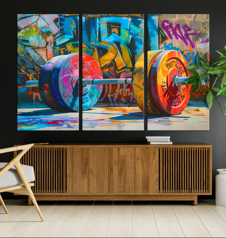 The Fitness Gym Barbell Graffiti Wall Art Canvas Print, a vibrant triptych featuring a barbell against a graffiti backdrop, elegantly hangs in the room. Crafted on premium canvas with a gallery-quality finish, this stunning piece of wall art effortlessly combines urban flair with sophisticated decor.