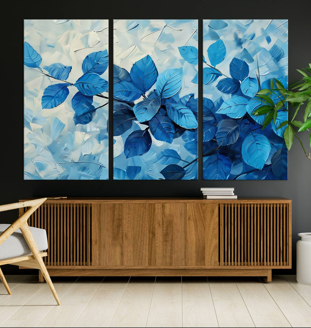 The contemporary living room is highlighted by the Abstract Blue Leaf Wall Art Canvas Print on the wall. The hand-assembled framed art enhances the room's vibrant decor, crafting a gallery-worthy ambience.