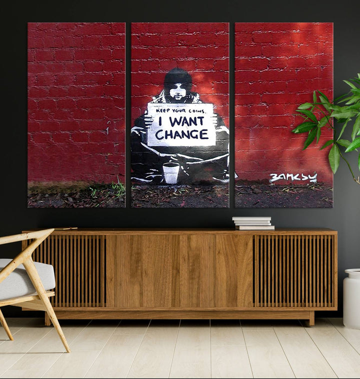 The living room showcases a triptych of stencil artwork on museum-quality canvas, featuring the Banksy I Want Change Graffiti Abstract Wall Art Canvas Print. This captivating piece depicts a person holding a sign that says "I want change" and is finished with a UV-protective coating to ensure long-lasting beauty.