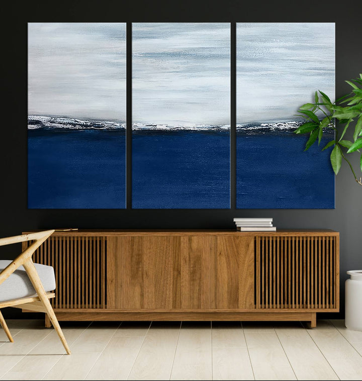 The modern living room is enhanced by the Navy Blue Abstract Wall Art Canvas Print on the wall, crafted as handmade wall art with a gallery-quality finish.